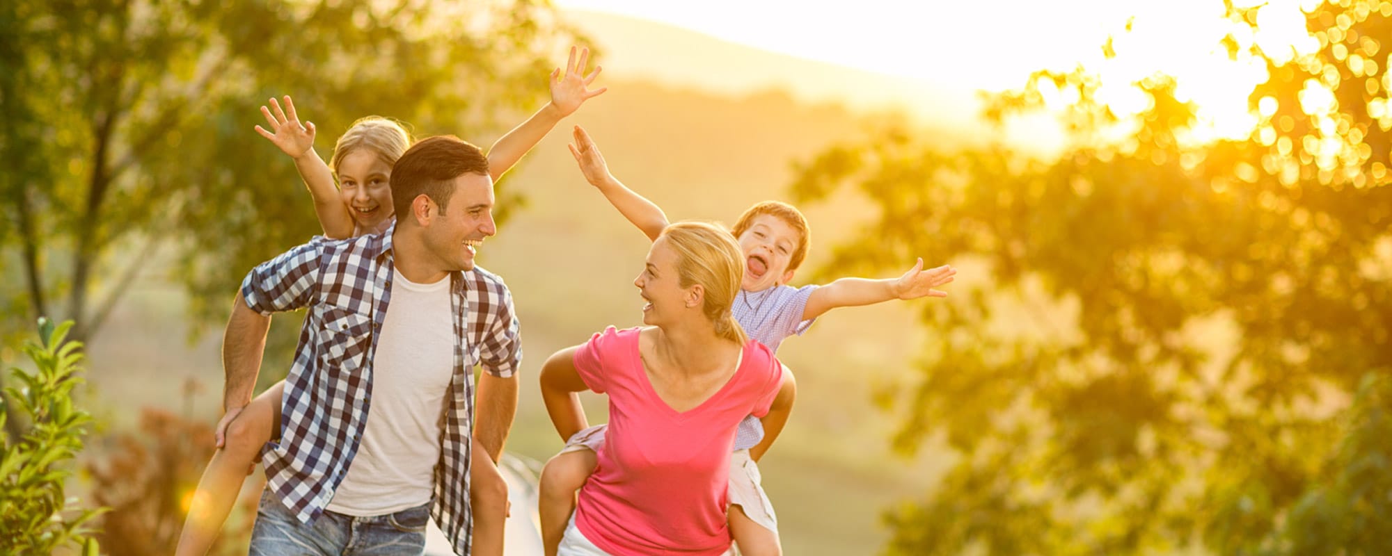 Image of a happy family walking through a medow during a sunset