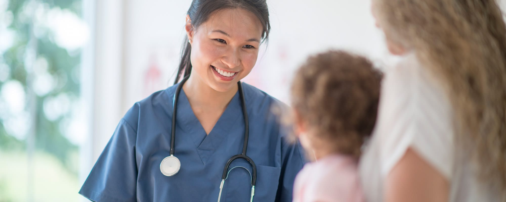 Image of smiling nurse consoling a little girl and her grandmother